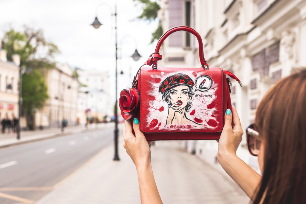 56d04657 woman holding her red and white leather handbag up high at 2304764