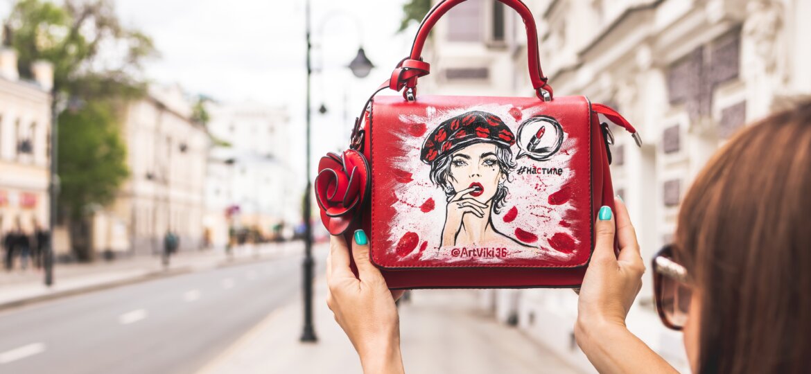 56d04657 woman holding her red and white leather handbag up high at 2304764
