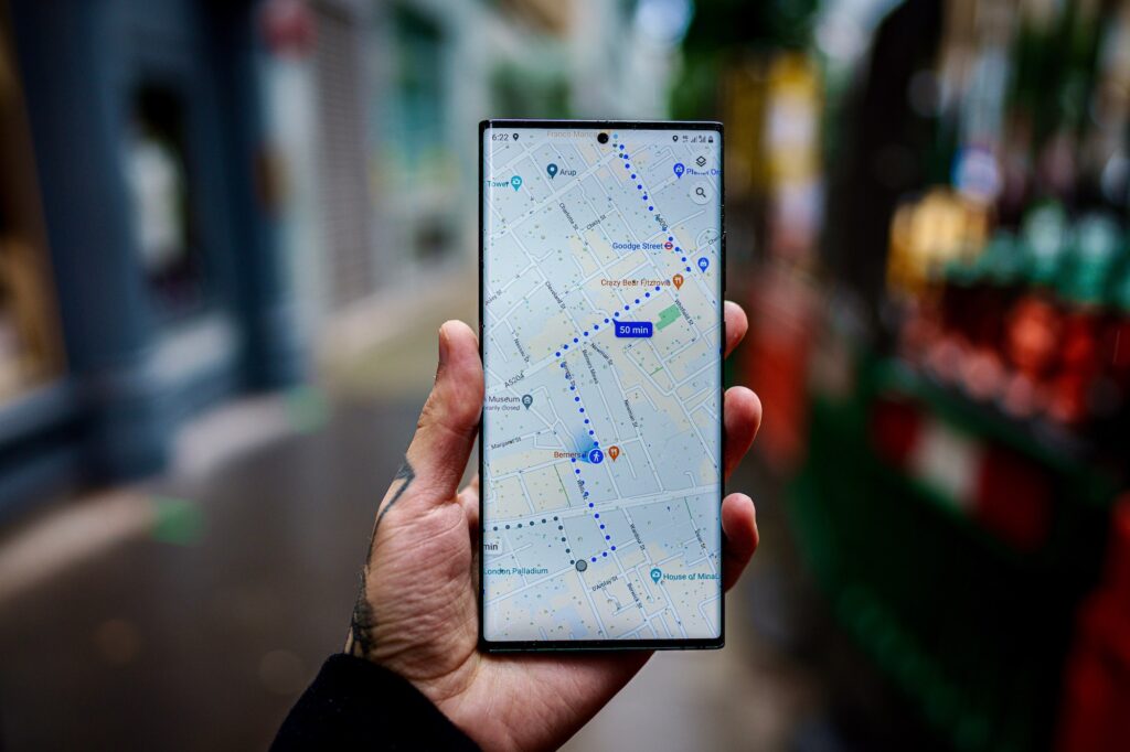 A person's hand holding a smartphone displaying a map with a walking route and estimated time of 50 minutes.
