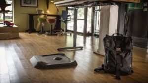 **Alt text:** A modern office space featuring a standing desk with a mat and a black backpack on the floor.