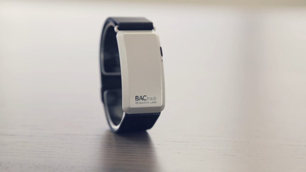 A close-up of a wearable black wristband with a white rectangular body, labeled "BACtrack Research Labs."