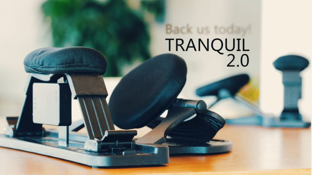 **Alt Text:** Close-up of ergonomic knee chairs with black cushions and the text "Back us today! TRANQUIL 2.0" in the blurred background.