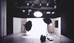A professional photography studio setup with large lights, softboxes, and a white backdrop.