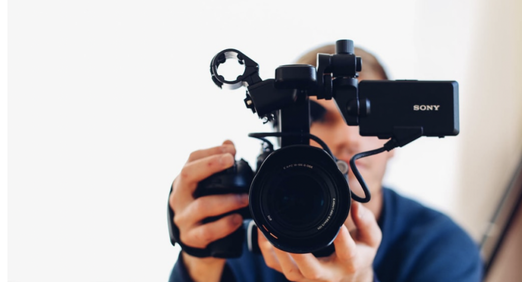 **Alt text:** A person is holding a Sony video camera, focusing directly into the lens.
