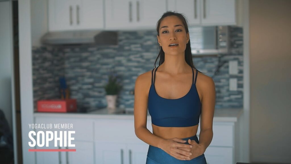 **Alt text:** A woman in a blue sports outfit stands in a kitchen with a serene expression.