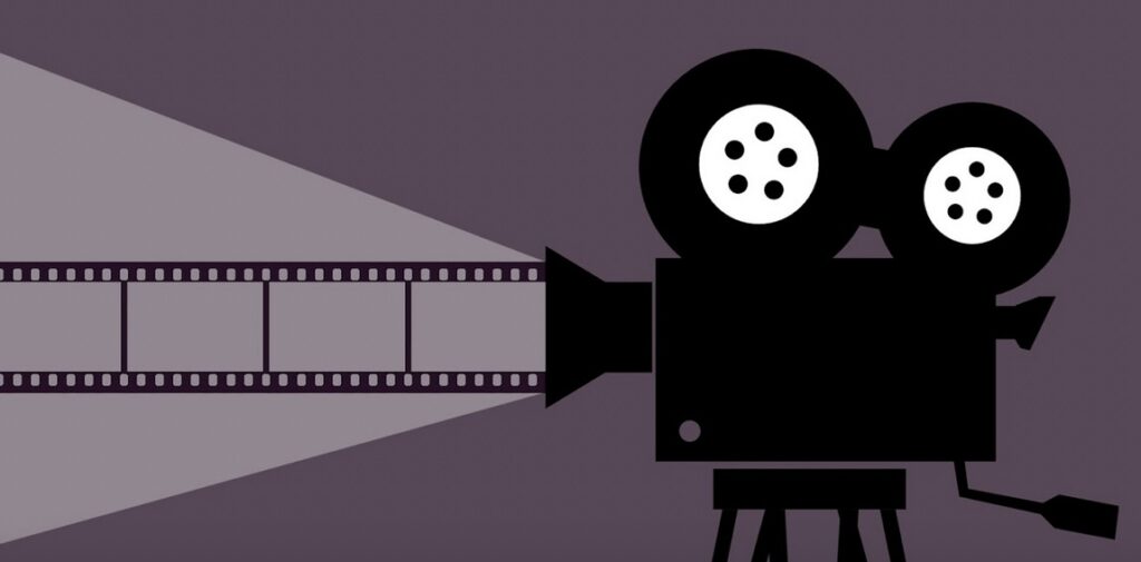 A silhouette of a vintage film projector casting a beam of light with a filmstrip visible against a dark background.