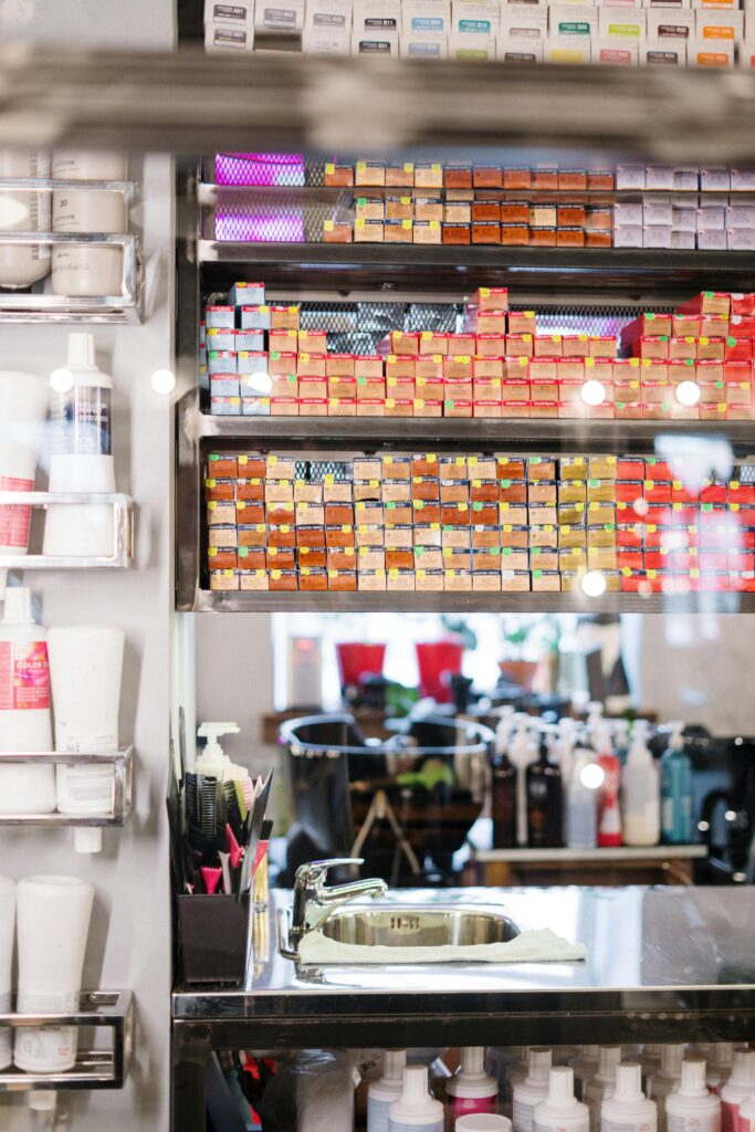 A hair salon storage area with shelves full of colorful hair dye boxes, hair care products, and a sink.