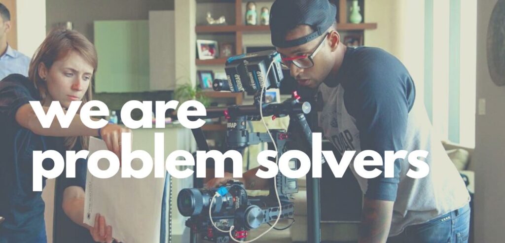 Two people work together adjusting a camera setup, with the text "we are problem solvers" overlaying the image.
