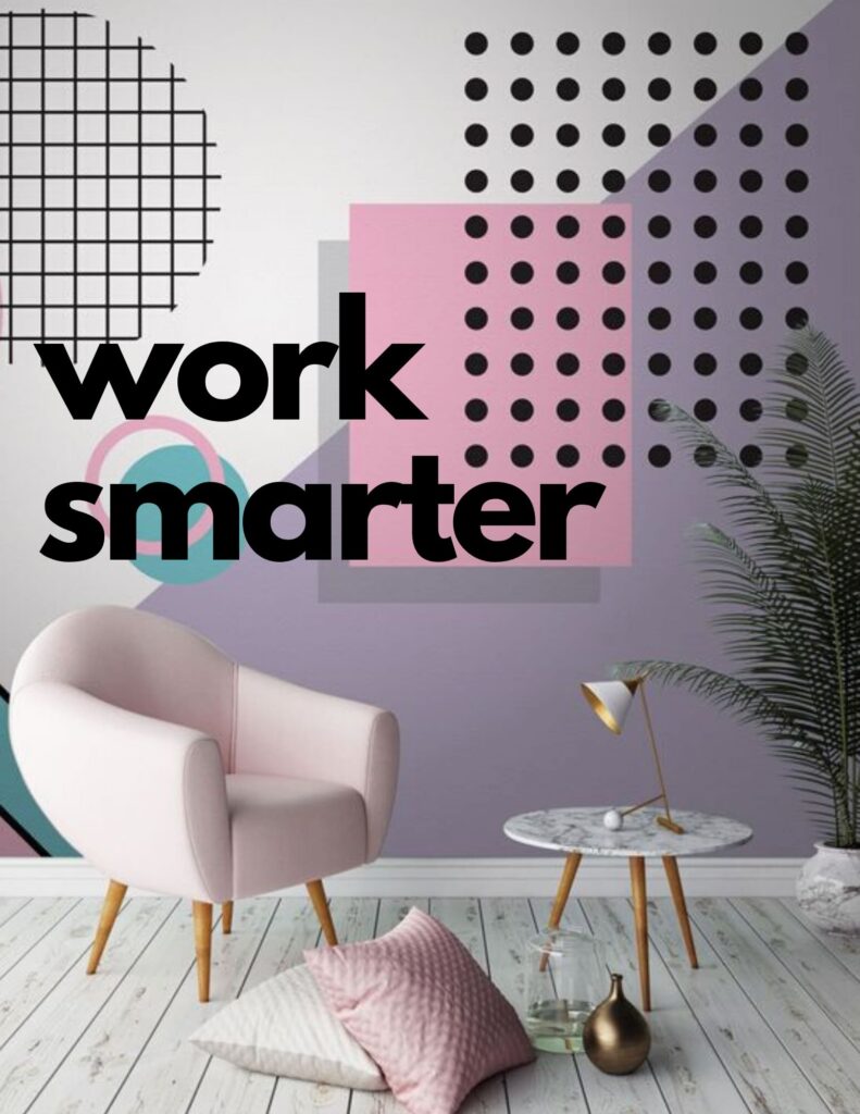**Alt text:** A minimalist room featuring a pink chair, patterned wall art with geometric shapes and the text "work smarter," a round side table with a lamp, and decorative pillows on a wooden floor.