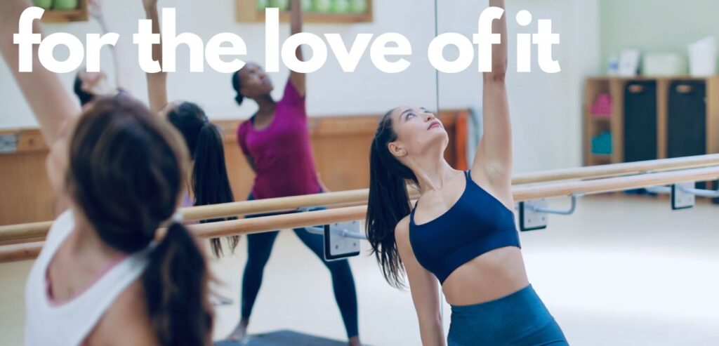A group of people participate in a dance or exercise class in a studio, with "for the love of it" written in large white text across the top.