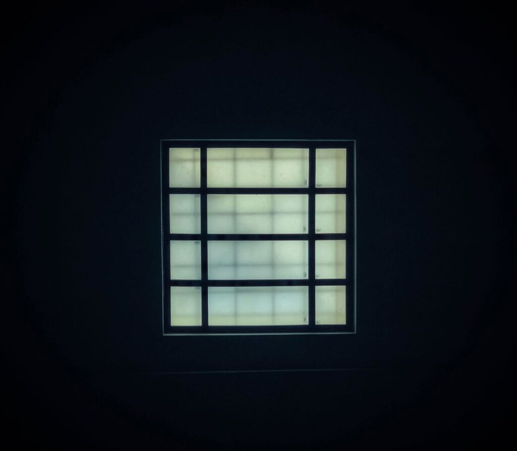 **Alt text**: A luminous square window with a grid pattern is centered against a dark background.