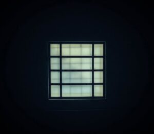**Alt text**: A luminous square window with a grid pattern is centered against a dark background.