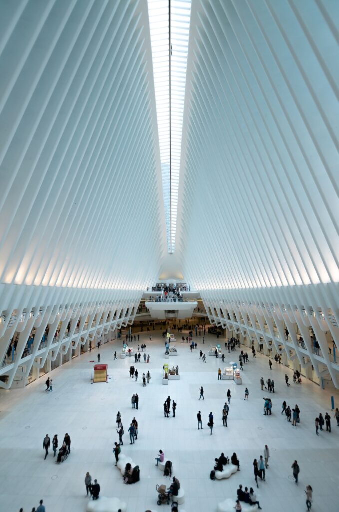 A wide-angle view of a spacious, modern architectural interior with high ceilings and a bustling crowd of people below.