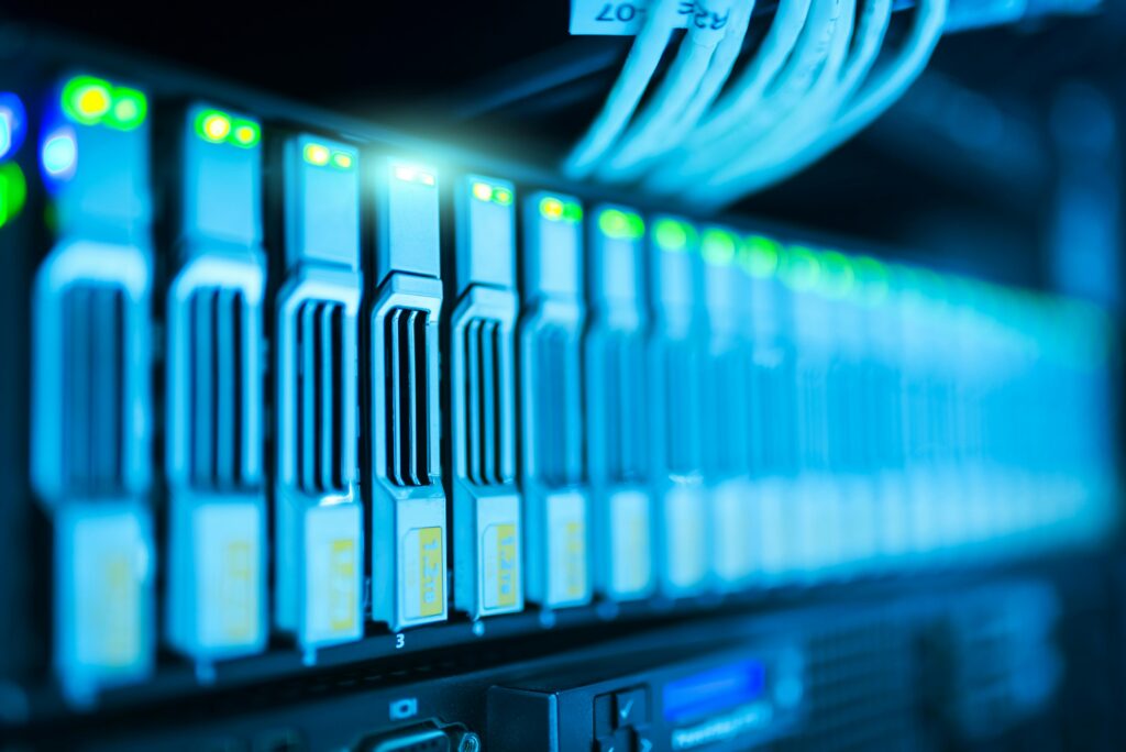 Close-up of a row of illuminated server racks with glowing green and blue lights.