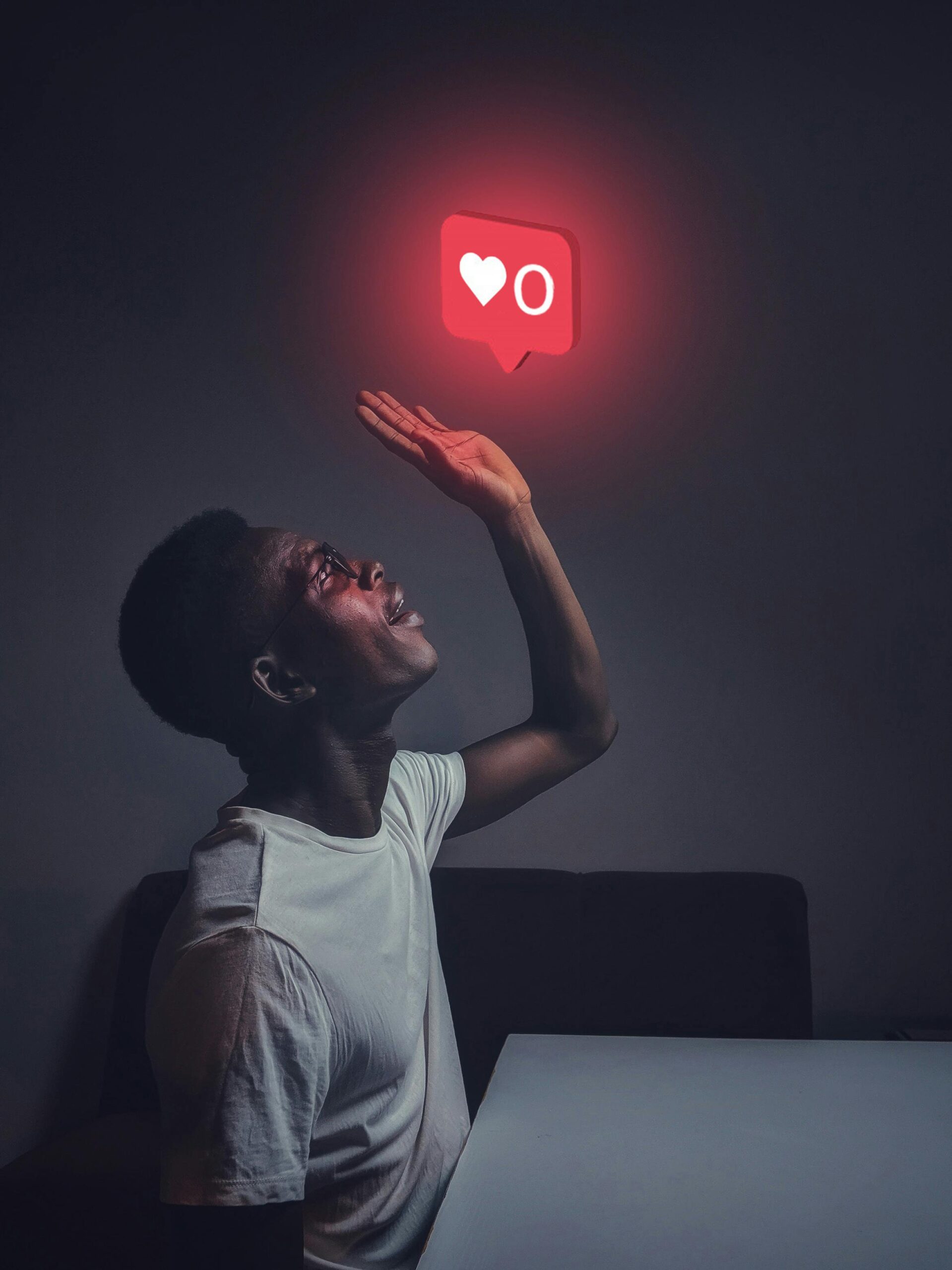 **Alt text:** A person gazes up at a glowing red notification bubble with a heart and the number zero, symbolizing social media likes.