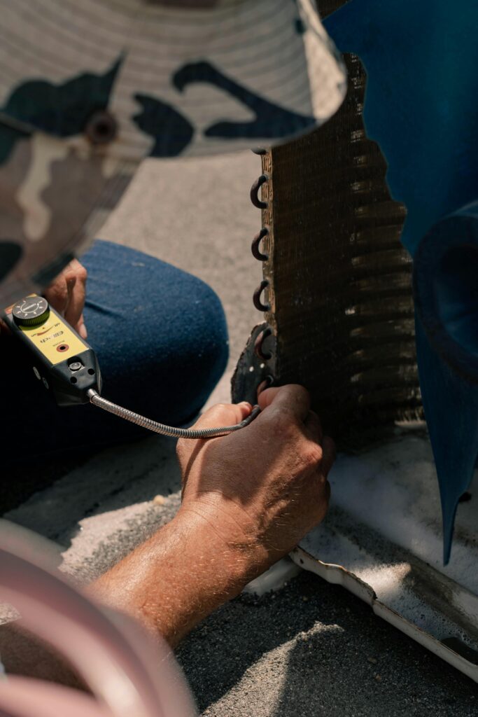 **Alt text:** A person in blue jeans kneels on the ground, using a handheld device to inspect the edge of a textured metal object.