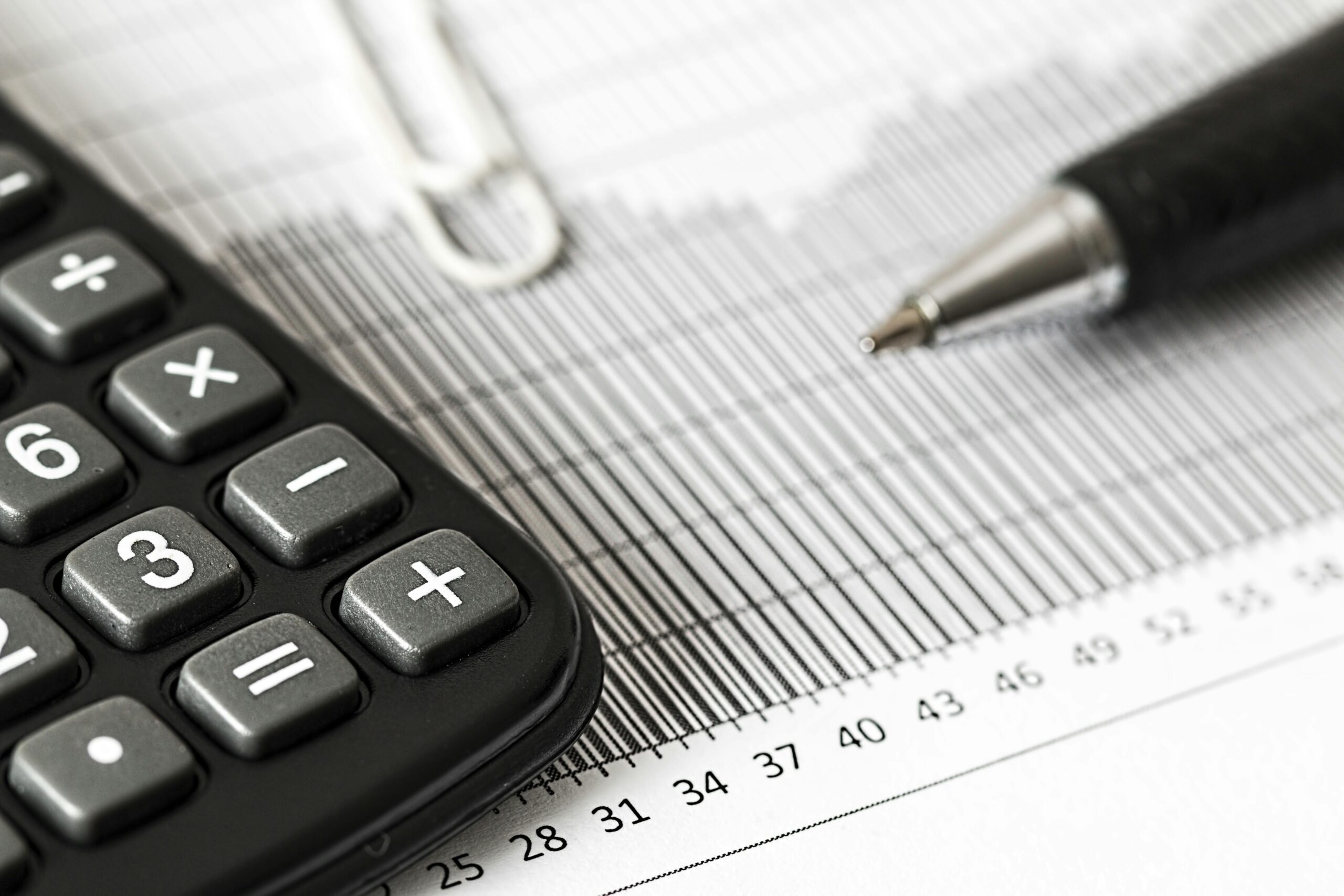 **Alt text:** A calculator, pen, and paperclip on a paper with a bar graph and numerical scale.