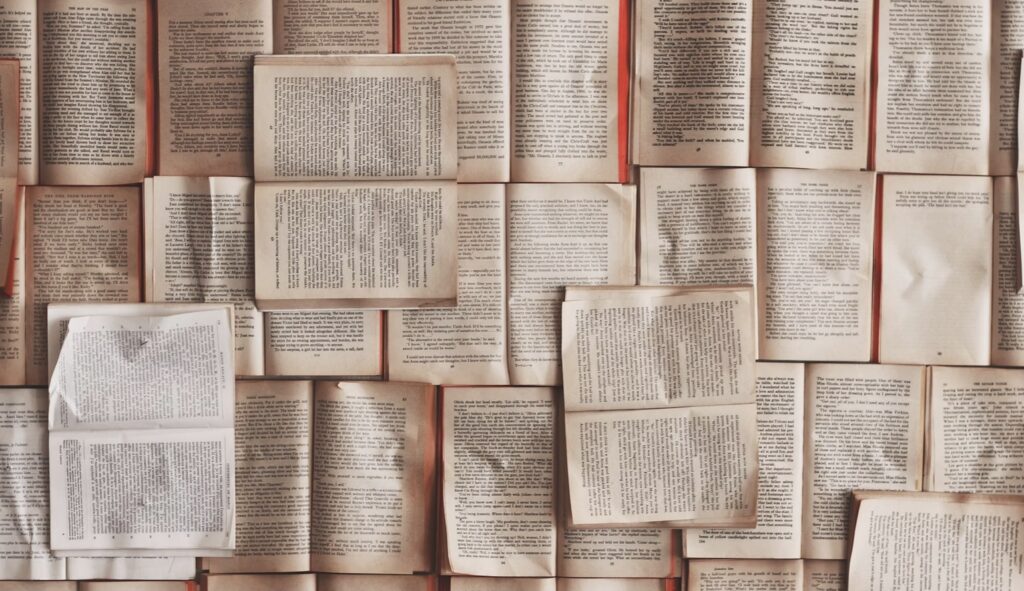 **Alt Text:** An arrangement of open books laid out side by side, displaying various pages filled with text.