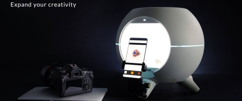 **Alt text:** A Foldio360 smart dome is shown next to a camera and a smartphone capturing an image inside the dome.