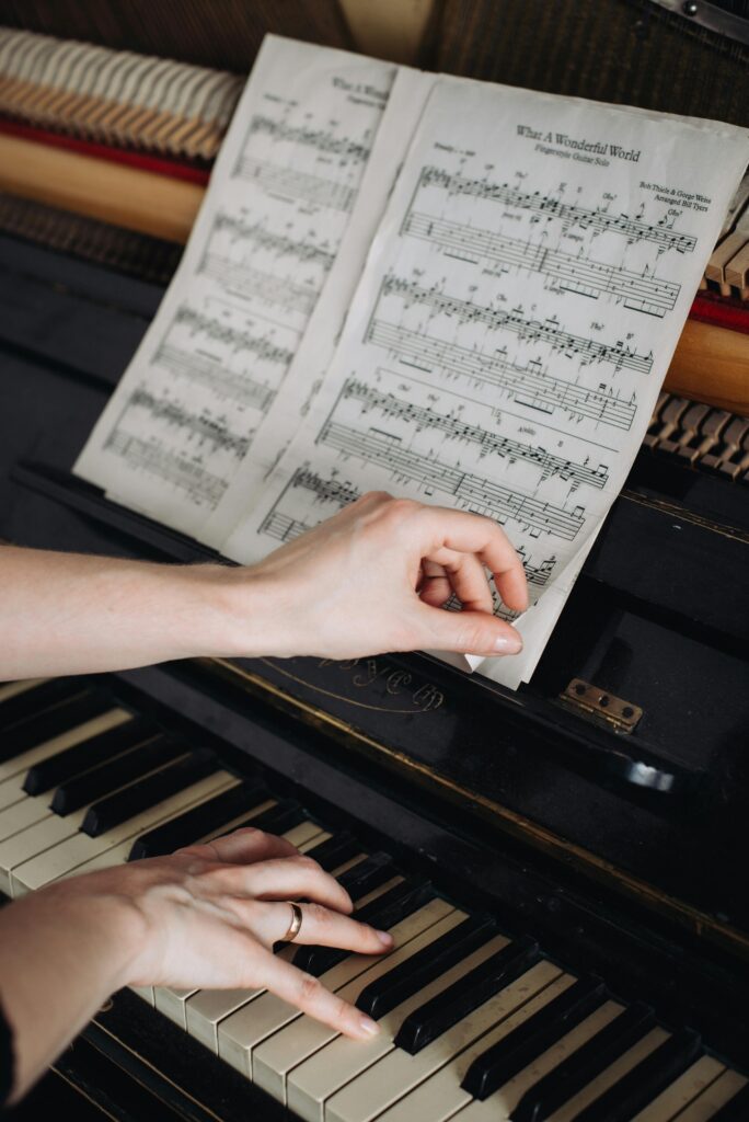 A person plays the piano while holding sheet music for "What a Wonderful World."