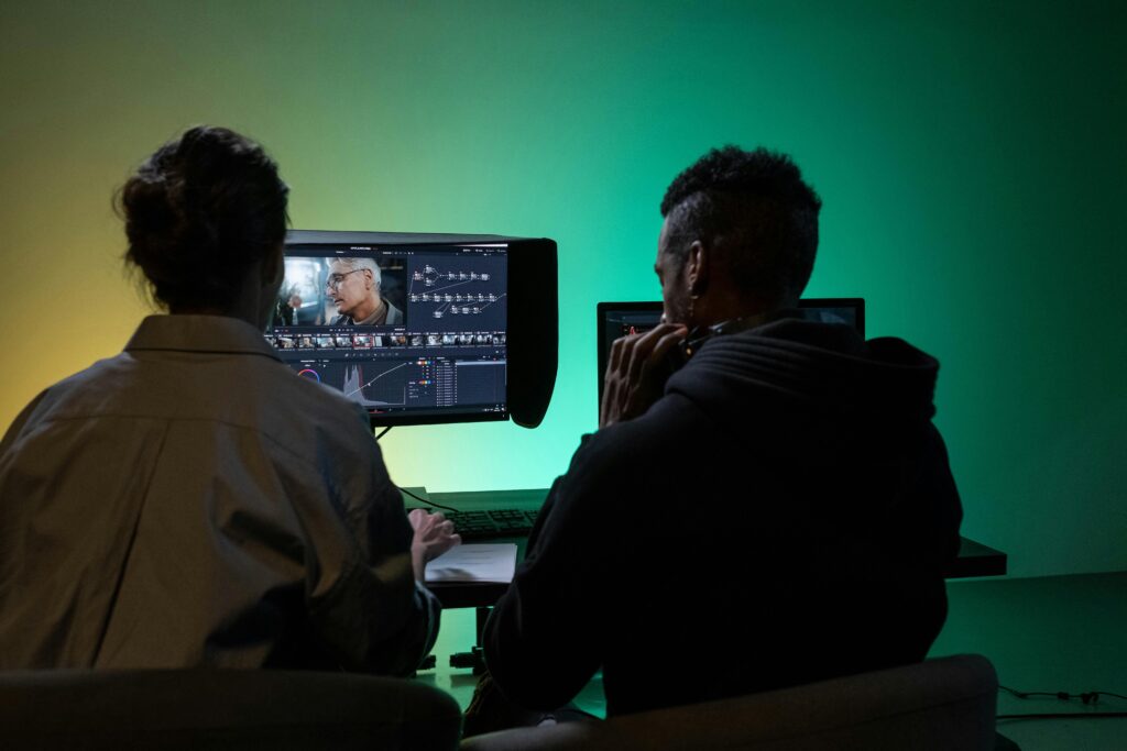 Two people work on video editing at a computer with a colorful background.