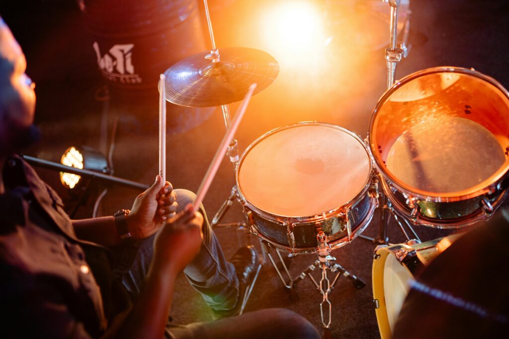 A person playing a drum set with a glowing light in the background.