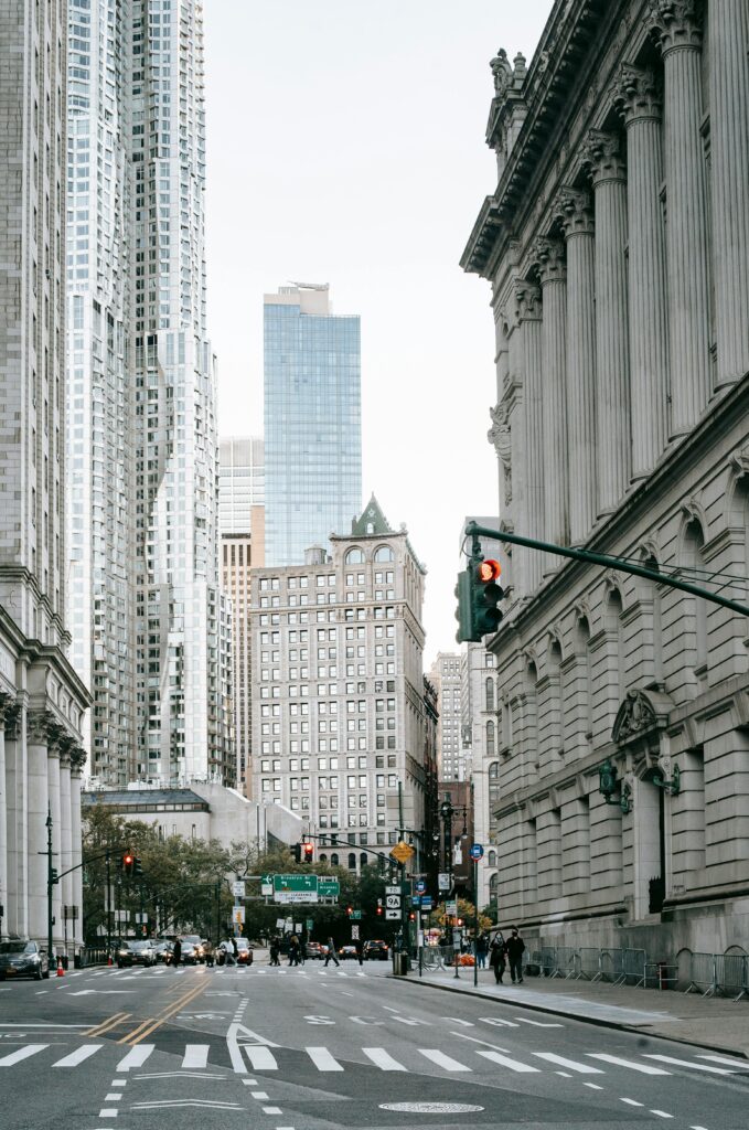 **Alt text:** A city street scene featuring a mix of modern and historic buildings, with a red traffic light in the foreground.