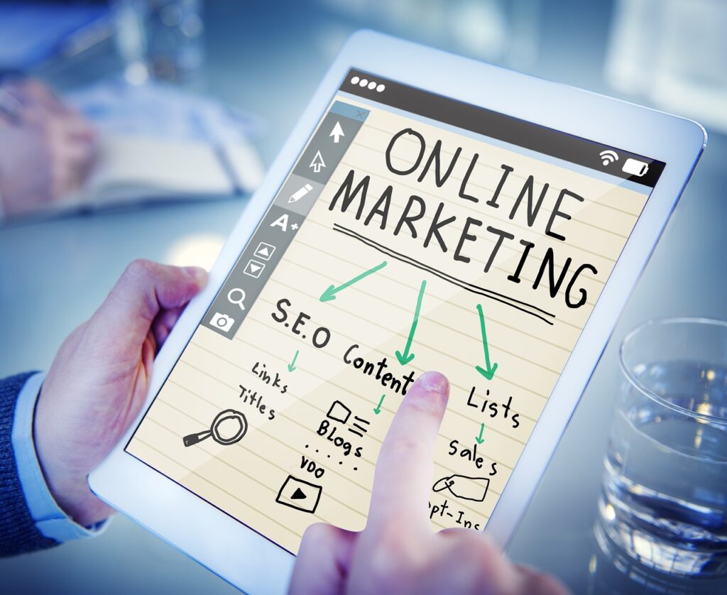 **Alt text:** A person holding a tablet displaying an online marketing diagram with words like SEO, content, and lists.