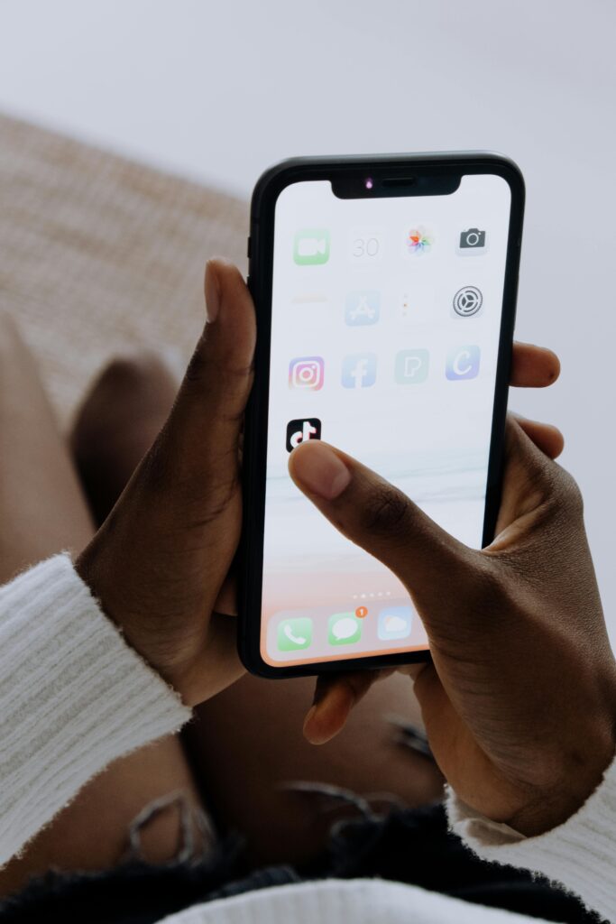 **Alt Text:** A person holding a smartphone with a close-up view of the home screen, showing popular app icons like TikTok and Facebook.