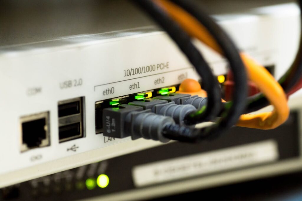 **Alt text:** Close-up of network cables plugged into an internet router with green indicator lights.