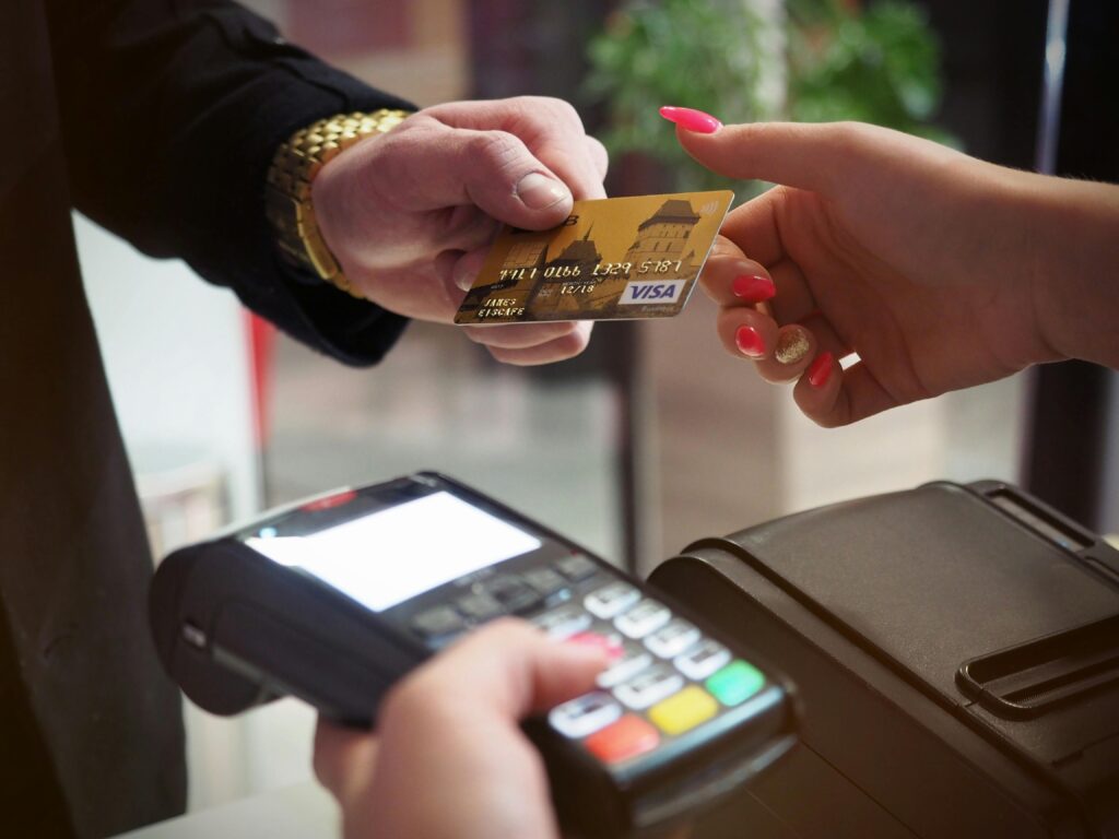 **Alt Text:** A person is handing a Visa credit card to another person at a payment terminal.