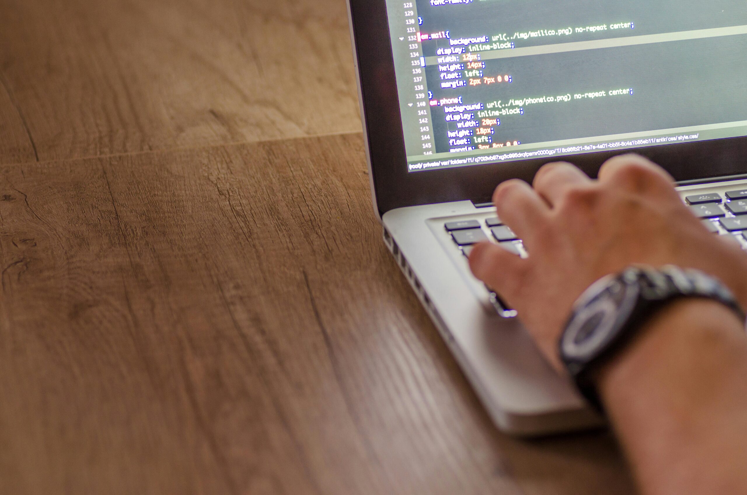 **Alt text:** A person typing on a laptop with code visible on the screen.