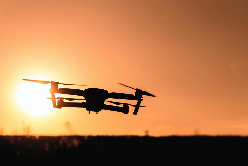**Alt text:** A drone is silhouetted against a vibrant orange sunset sky.