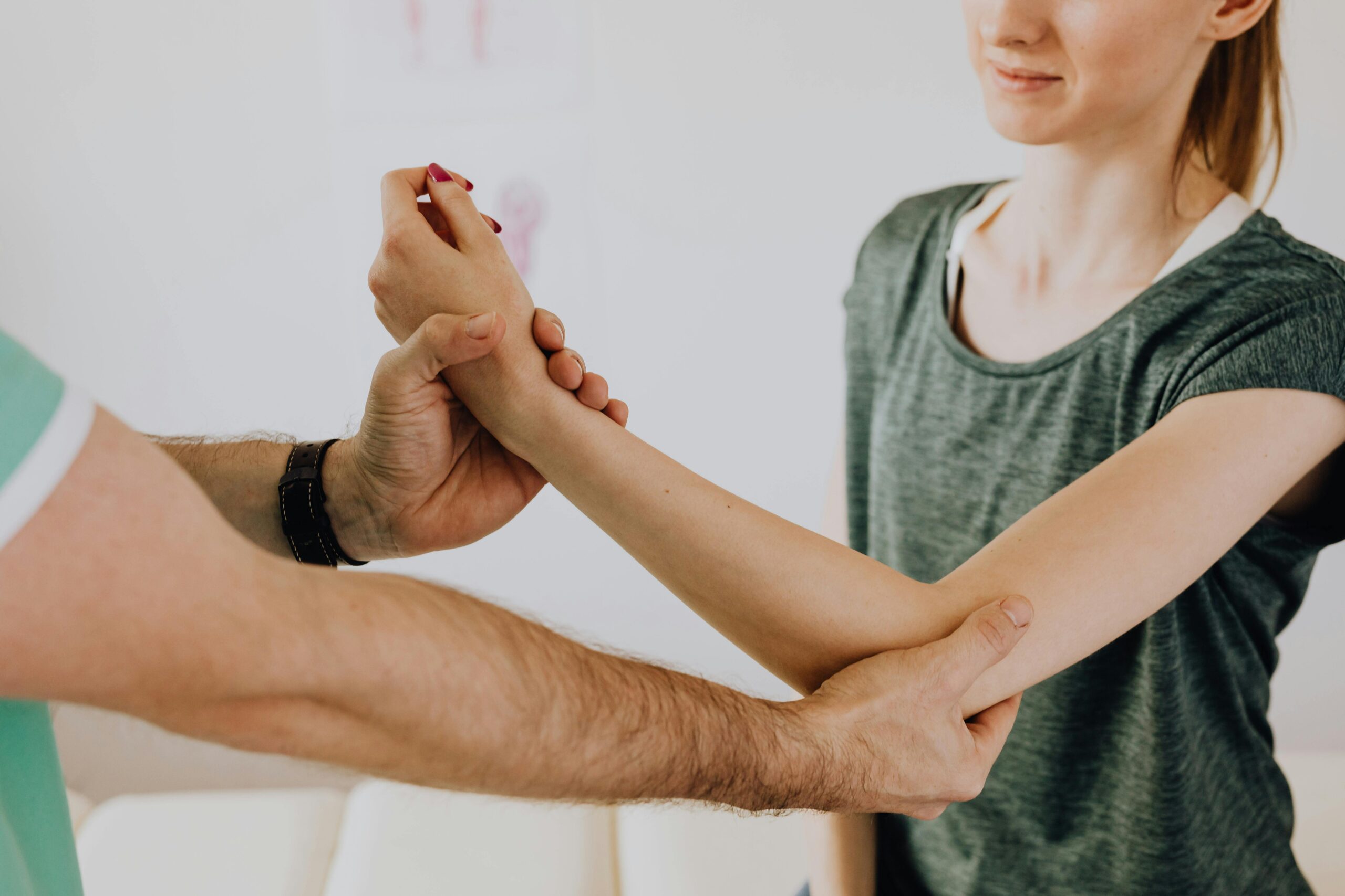 A therapist holds and stretches a woman's arm during a physical therapy session.