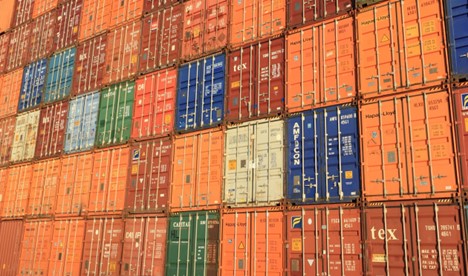 **Alt Text:** A large stack of multicolored shipping containers tightly arranged in rows.