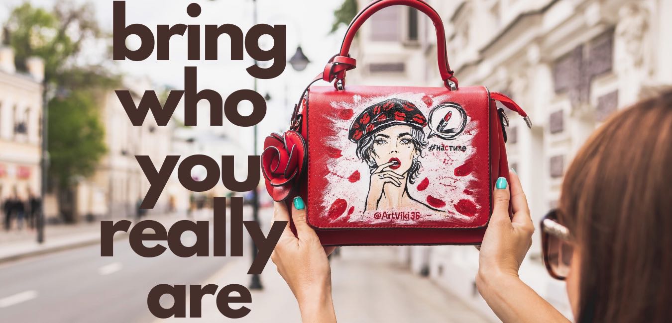 A person holds up a red handbag with an illustrated design of a woman with red lips and beret, accompanied by the text "bring who you really are" on the left side.