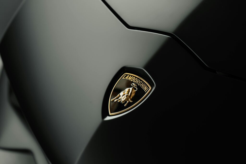 Close-up of a Lamborghini logo on a sleek, dark car surface.