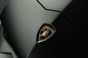 Close-up of a Lamborghini logo on a sleek, dark car surface.