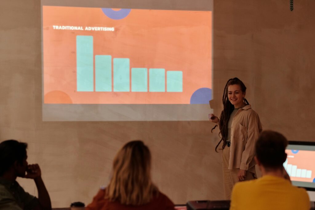 A person gives a presentation on traditional advertising, showing a bar graph on a projector.