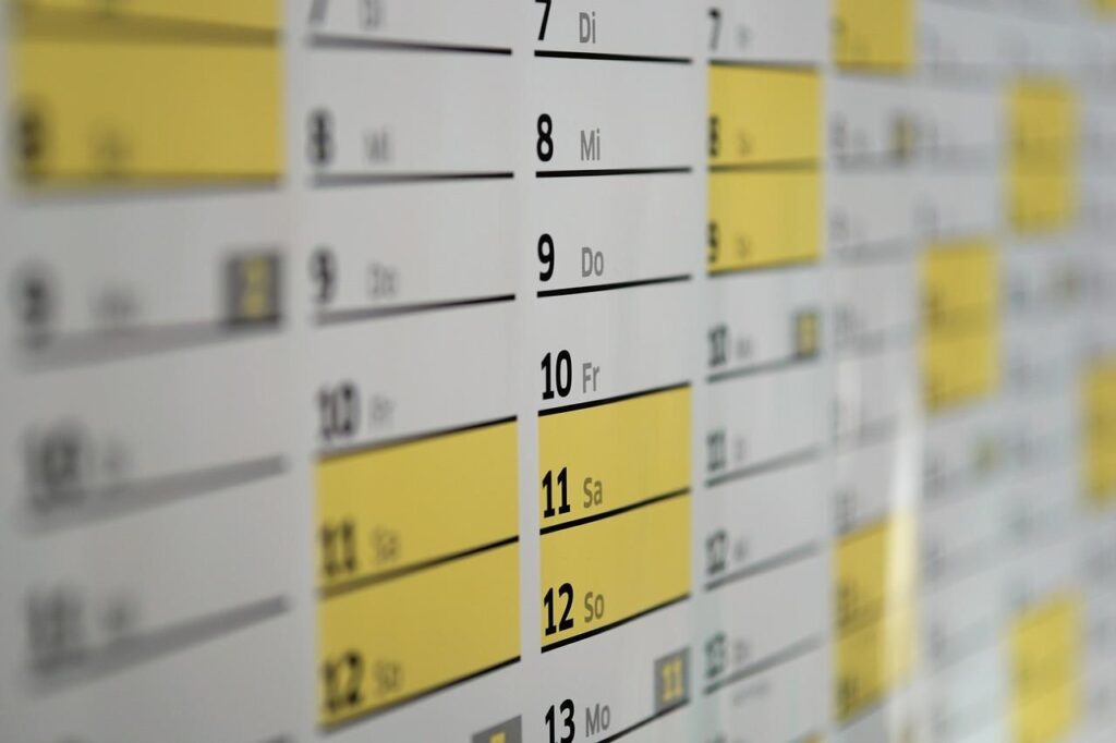 **Alt text:** A close-up of a wall calendar showing days of the week and numbers, with certain dates highlighted in yellow.