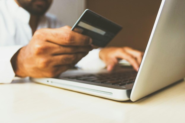 **Alt Text:** A person using a credit card while typing on a laptop.