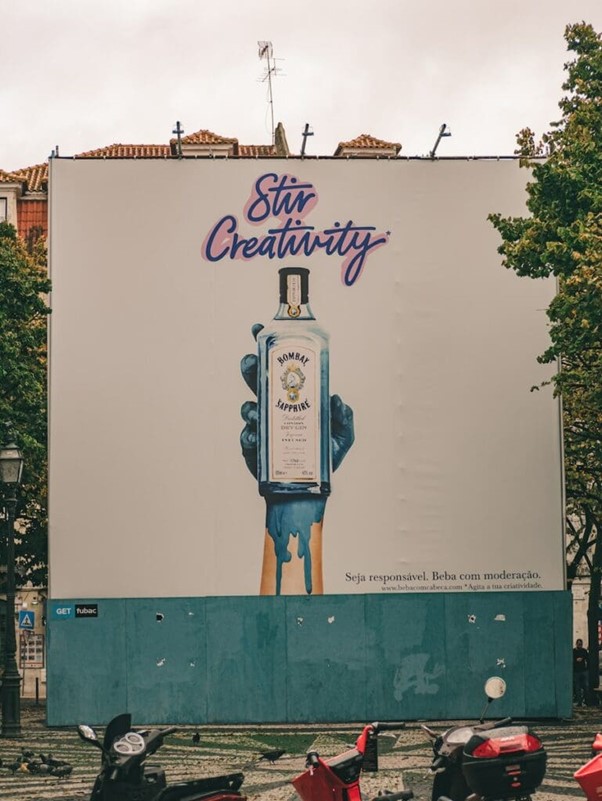 A large billboard displays a hand painted blue holding a bottle of Bombay Sapphire gin with the words "Stir Creativity" above it.