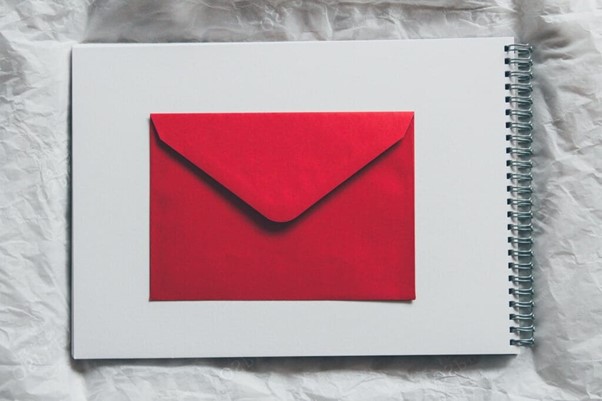 A red envelope on top of a spiral-bound notebook with a white cover.