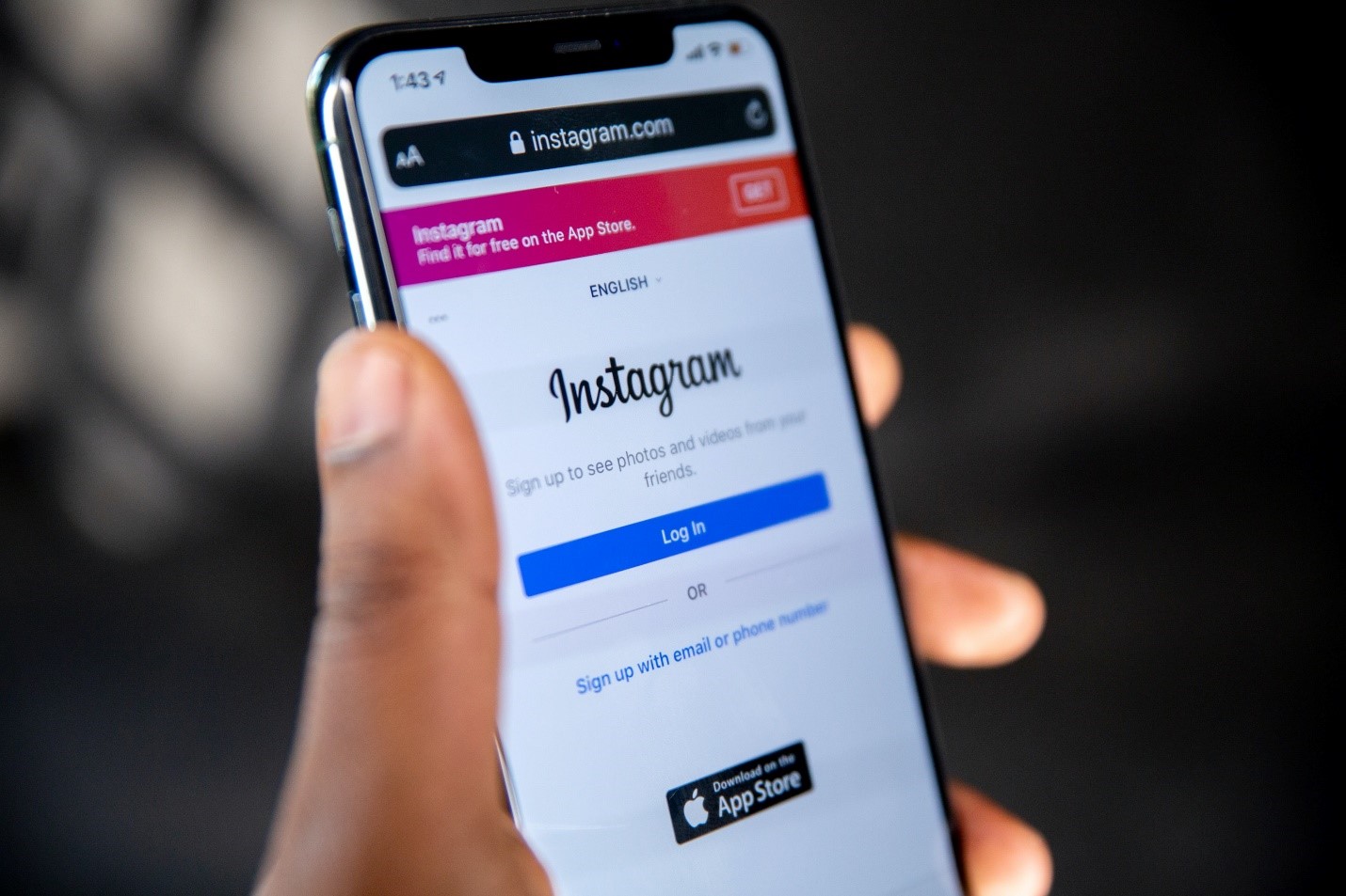 A person holds a smartphone displaying the Instagram login page.