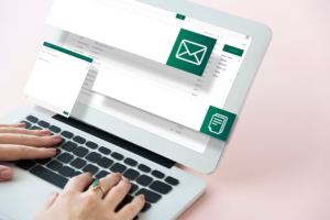 A person typing on a laptop displaying an email application interface with large icons for composing and sending messages.