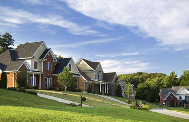 **Alt text:** A row of suburban houses with well-maintained lawns and a clear blue sky.