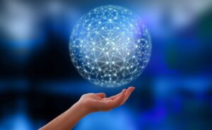 **Alt Text:** A hand is holding a glowing digital sphere composed of interconnected nodes against a blurred blue background.