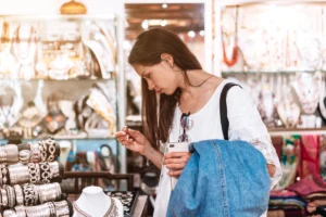 A woman is shopping for jewelry, examining a ring in a store filled with various accessories.