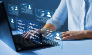 **Alt Text:** A person is using a laptop, with virtual screens displaying digital profiles and checklists hovering above the keyboard.
