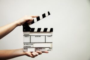 A person holds a film clapperboard against a plain white background.